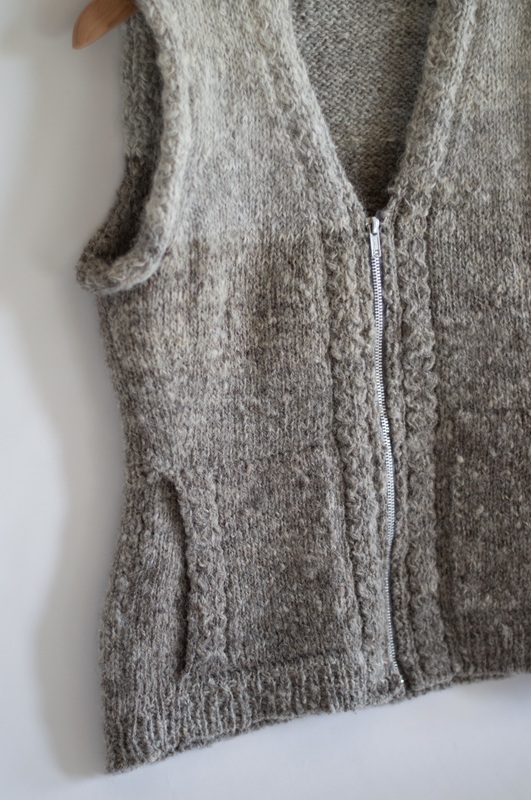 Detail of vest knitted with local, handspun Jacob wool. This vest features subtle cables, color gradient, pockets, and a zipper.